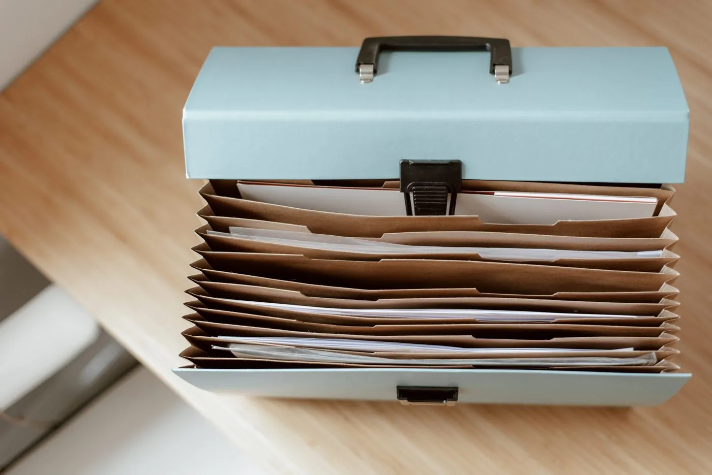Boîte à dossiers ouverte, chemises cartonnées classées sur un bureau clair