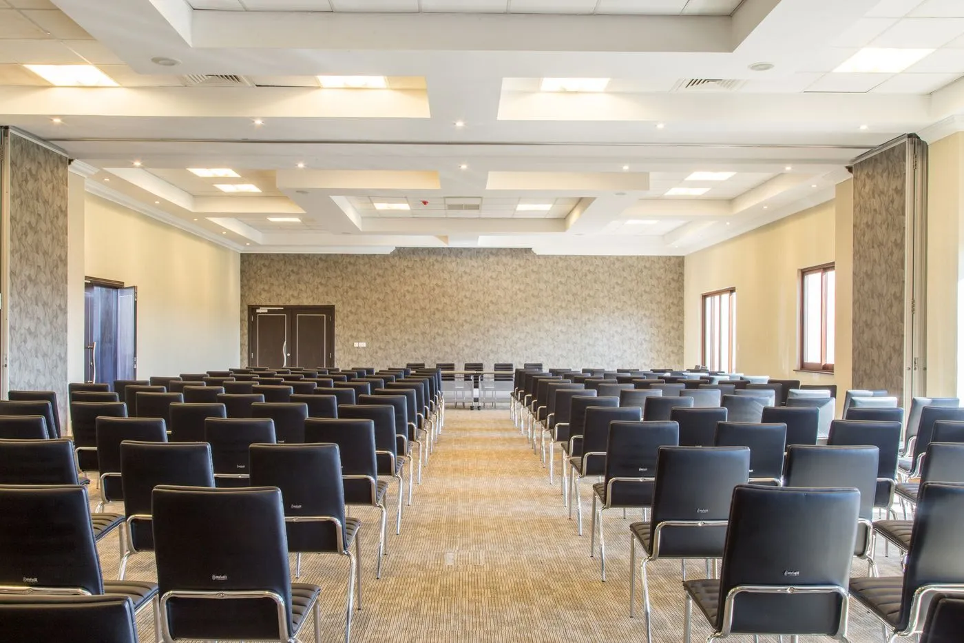 Salle de séminaire installée, rangées de chaises face à l’estrade