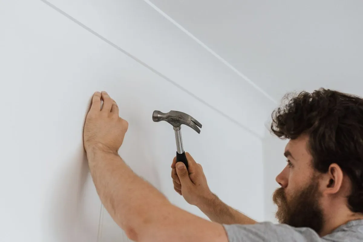 Artisan plantant un clou dans un mur clair