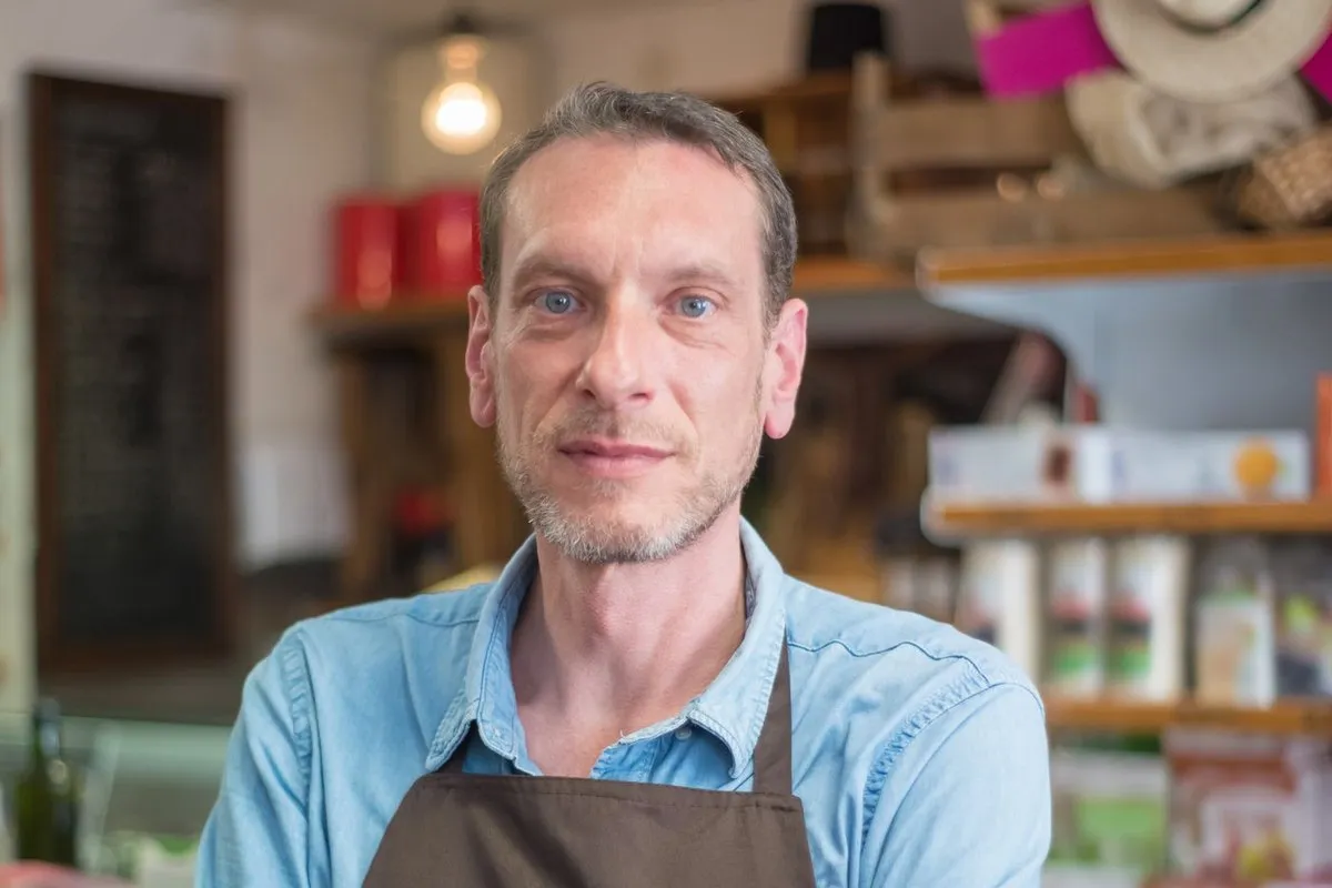 Commerçant en tablier dans sa boutique, bras croisés
